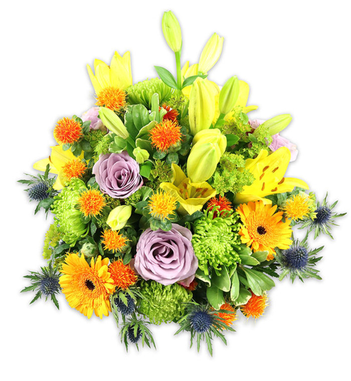 Presented on a stark white background so every hue and texture is visible, this richly packed bouquet reads as a celebration of colour and florist skill familiar to the streets around Enfield Wash and the Lee Valley. Several yellow Asiatic lilies form vertical focal points-some fully unfurled with their characteristic speckling and open throats, others held as tender, elongated buds that suggest future bloom and gentle movement. Two or three soft lavender-purple roses rest slightly lower in the composition; their layered petals create a calming, romantic centre and a subtle perfume note imagined through the visual cues. Large orange gerbera daisies, their ray-like petals radiating from darker centres, scatter warmth across the arrangement, counterbalanced by abundant chartreuse-green button chrysanthemums which give the bouquet its lush, almost mossy volume. Small spherical spiky accents in vivid orange and golden-yellow are dispersed through the mass, adding playful texture and contrast to the larger blooms. Defining the composition's edges are cool blue-grey Eryngium sea thistles, their star-shaped bracts and rigid stems offering a sculptural coolness against the warmer tones. A mix of broad lily leaves and smaller glossy filler foliage knits everything together, producing depth and natural flow. The overall impression is one of joyful elegance-suitable as a congratulatory gift, a bright sympathy offering, or a striking table centre-and reflects the kind of carefully arranged bouquets Florist Enfield Wash prepares for local delivery across Enfield Town, Ponders End, and the surrounding neighbourhoods.